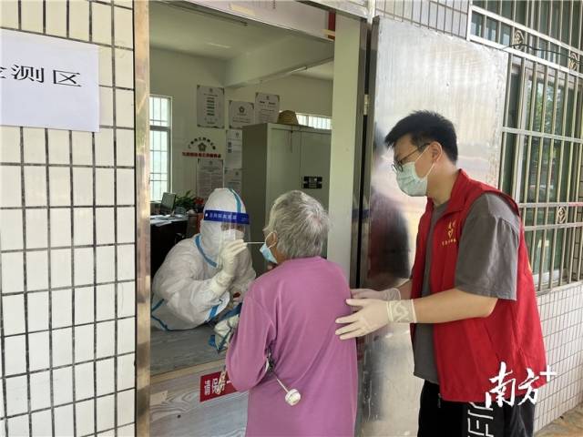 現(xiàn)場志愿者幫助行動不便群眾接受核酸檢測。
